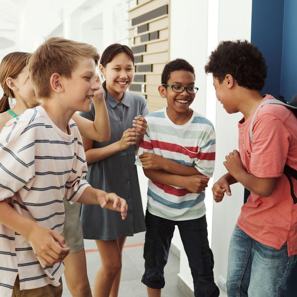 Group of diverse children laughing while doing yoga together.