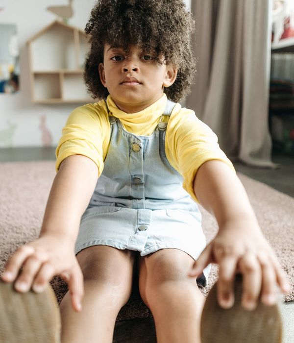 Happy child in a playful yoga pose in a bright room.
